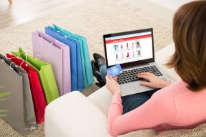 Young Woman On Sofa Shopping Online With Debit Card